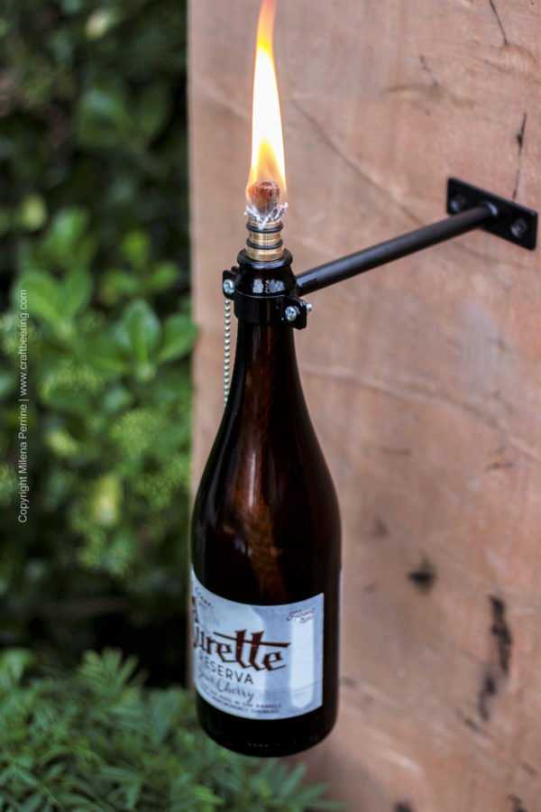 Beer bottle tiki torch mounted on wall using this kit: http://amzn.to/2uVHs8Y