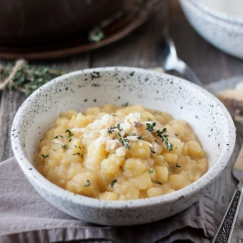 Bowl of cheesy potato risotto with Pilsner magic. Creamy, black pepper coated Toscano cheese. #beerrisotto #potatorisotto #cookingwithbeer #cookingwithbeerrecipes #thyme