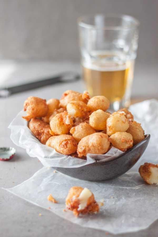 Fried cheese curds! Our recipe encases them in a crispy, light beer batter | A bowl full of delicious, golden beer battered fried cheese curds is exactly what your cold beer needs:) #cheesecurds #friedcheesecurds #beerbattered #appetizer #gamedayfood #beergardenfood #friedcheese