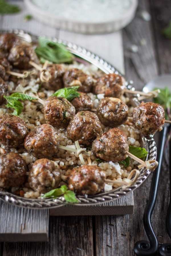 Lamb meatballs with feta, cumin and Pilsner served over a platter of buttery couscous with pine nuts, feta and mint. Lamb recipe heaven! #lambmeatballs #lambrecipe #cumin #lambrecipe