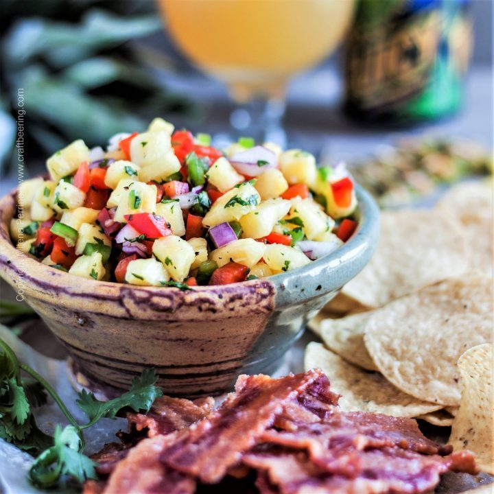 Pineapple salsa in a bowl served with bacon chips and tortilla chips