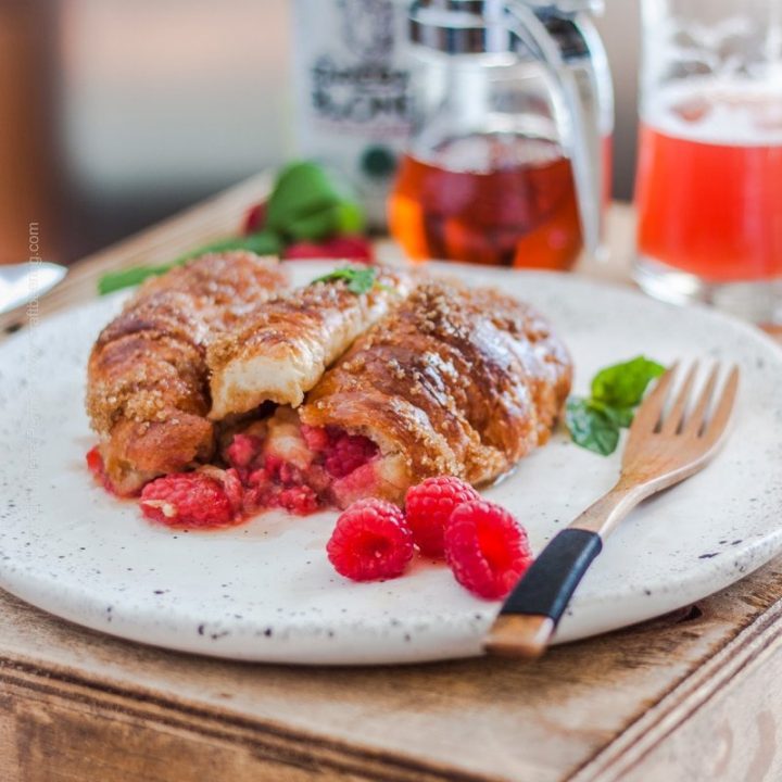 Croissant French toast stuffed with raspberries and served topped with raspberries and drizzled with maple syrup.