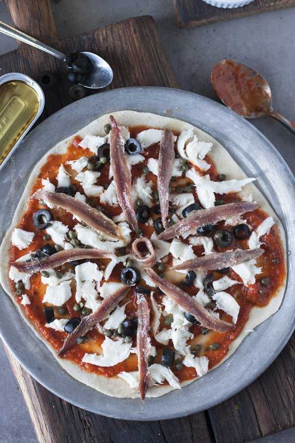 Anchovy pizza with marinara and mozzarella ready to go in the oven.