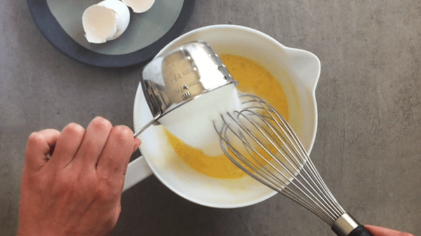 Add sugar to the beaten eggs.