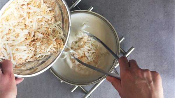 Shredded cheese is folded into beer and cream mixture for beer cheese fondue.