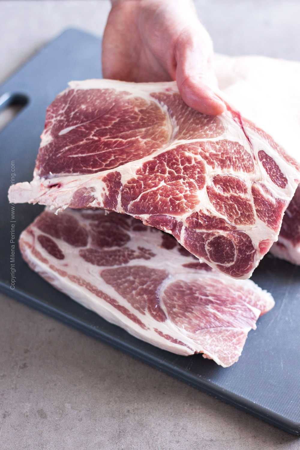 Raw pork shoulder blade steak carved from a whole bone in pork shoulder.