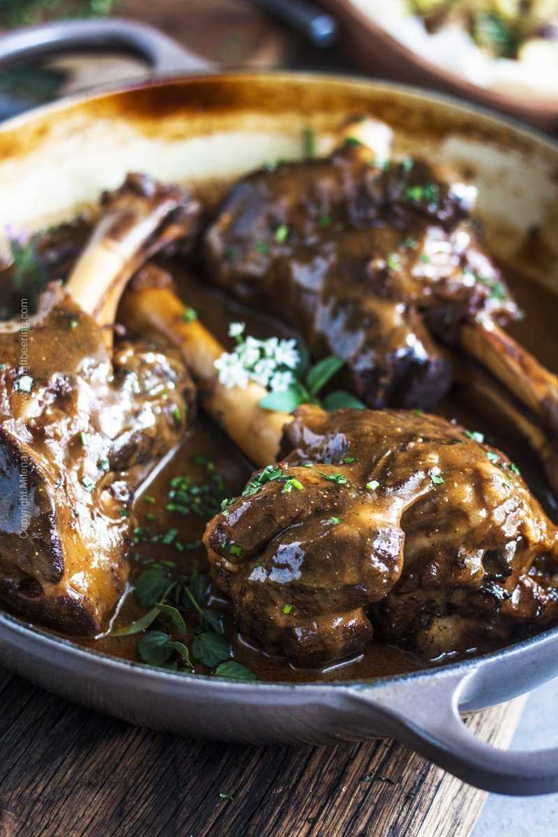 Close up of a perfectly braised lamb shank with fall off the bone tender meat.