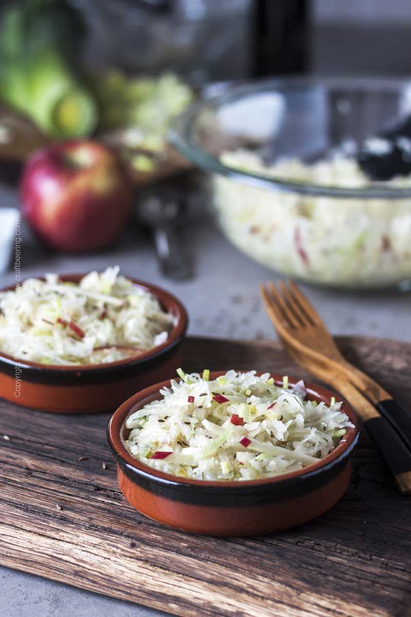 Sauerkraut salad with apples and leeks served in small plates and topped with caraway seed.