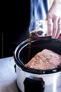 Cooking with beer - brown ale is poured into a crock pot for beer pulled pork.