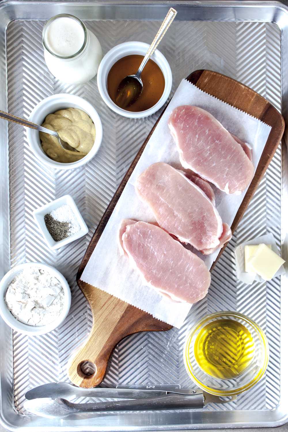 Raw boneless thin pork chops with other ingredients needed for pan searing them and making a creamy honey mustard pan sauce. 
