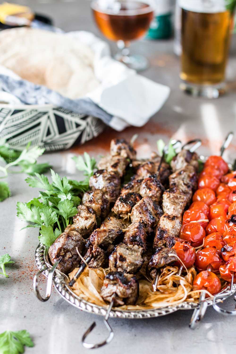 Platter with lamb shish kebab traditionally presented with roasted toamato skewers, shaved onions and sumac, parsley and flat bread.