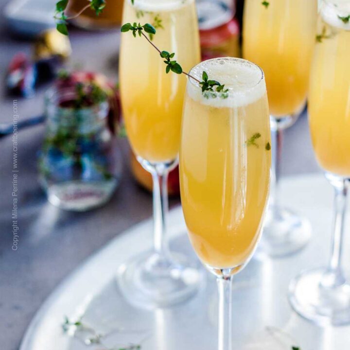 Fresh Peach Bellini Cocktail in flute glasses garnished with thyme