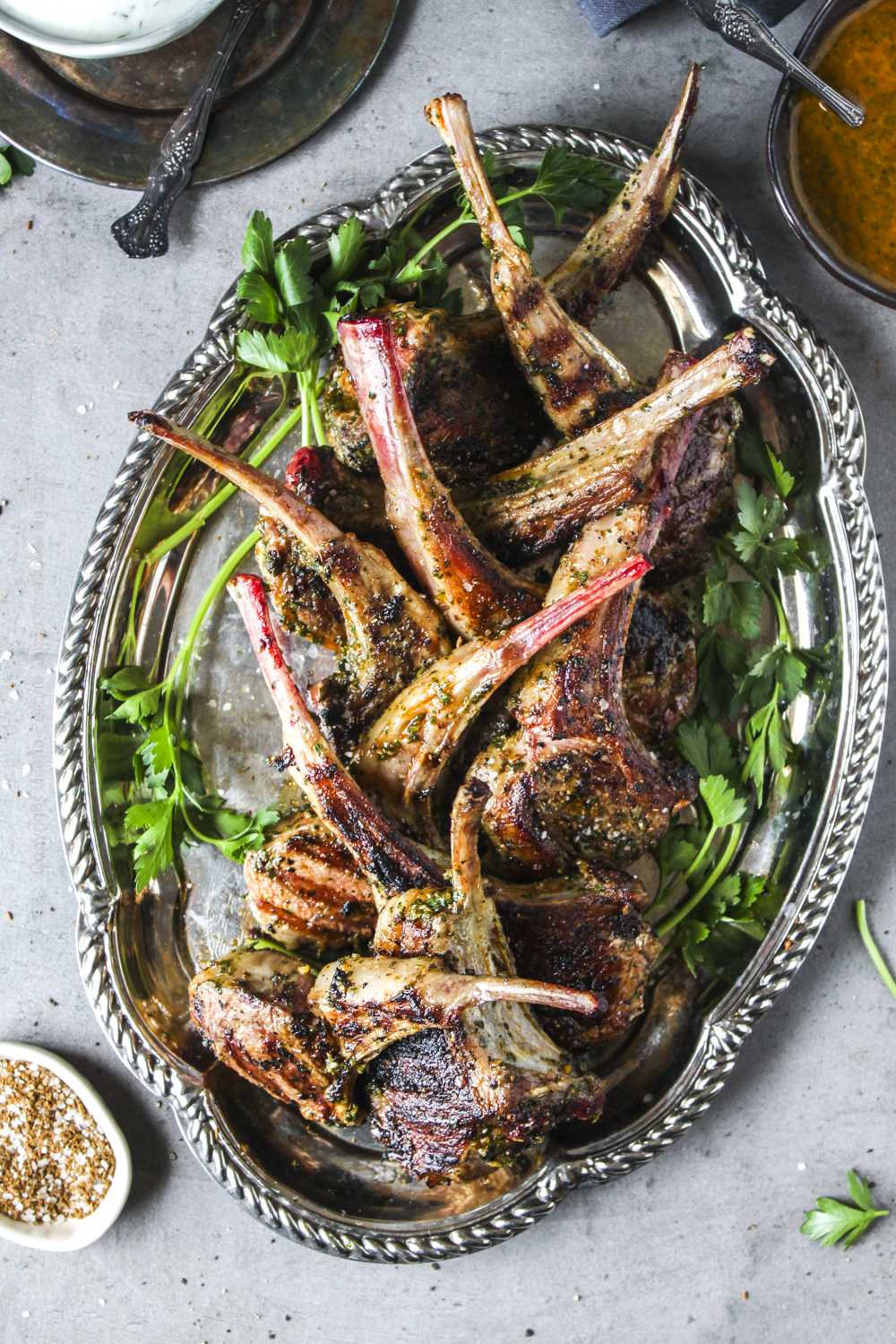 Pan seared lamb rib chops arranged on a platter with two dipping sauces - Moroccan chermoula nd yogurt garlic.