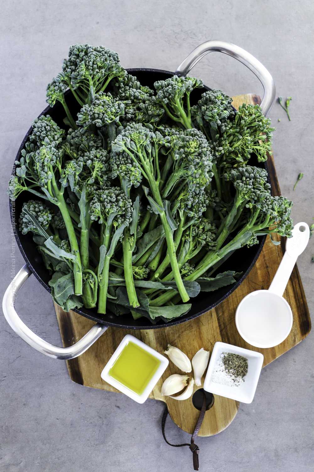 Raw broccolini in a pan with olive oil, garlic, S&P and water for steaming. 