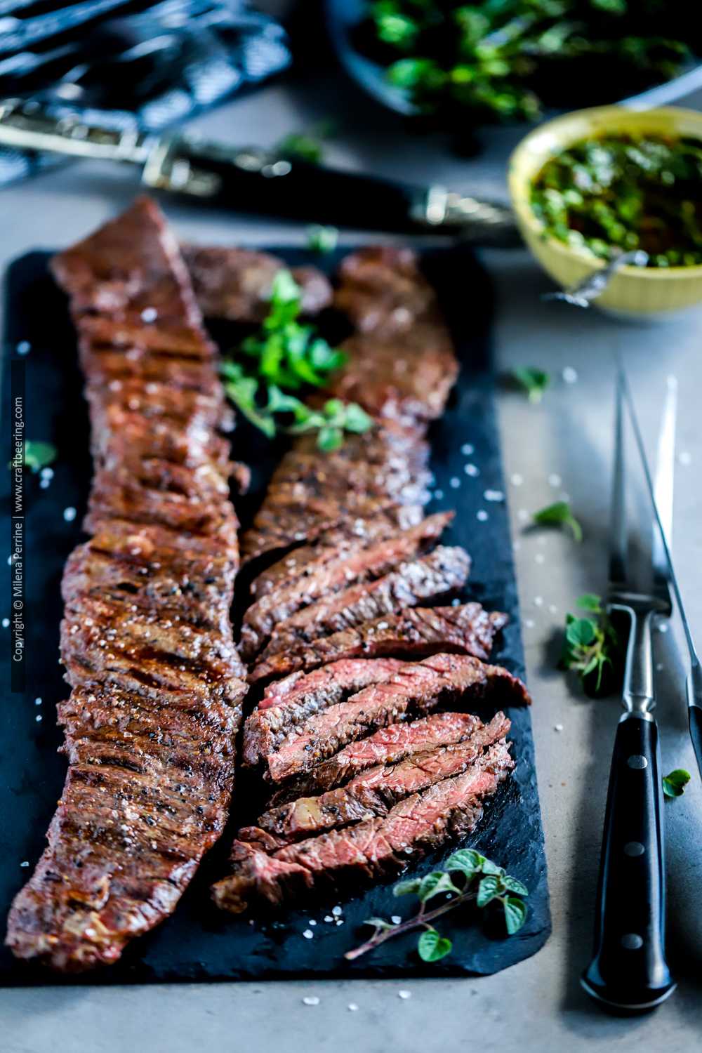 Outside skirt steak served family style with bowl of chimichurri .