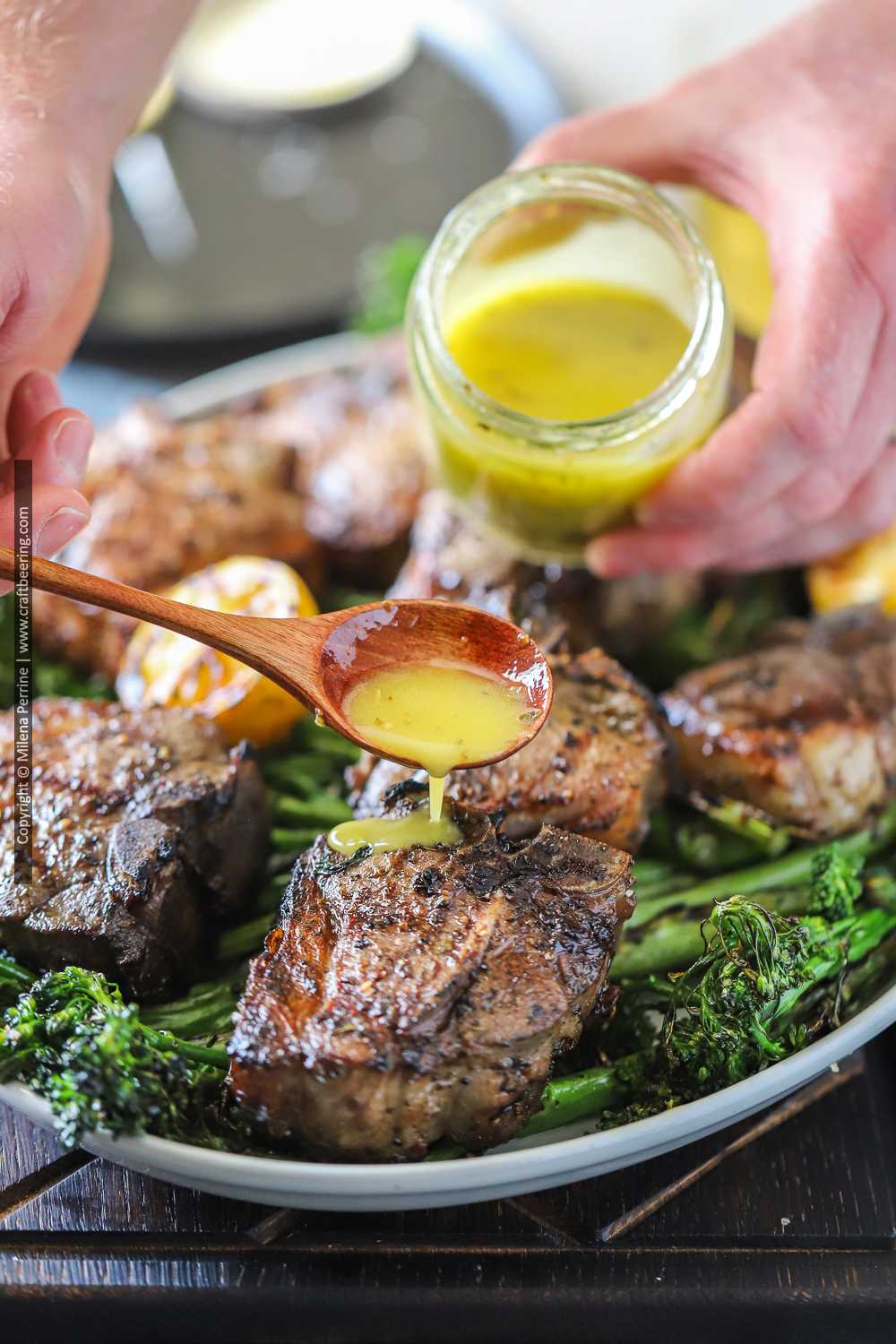 Grilled lamb loin chops on platter with lemony sauce for lamb chops drizzled over them