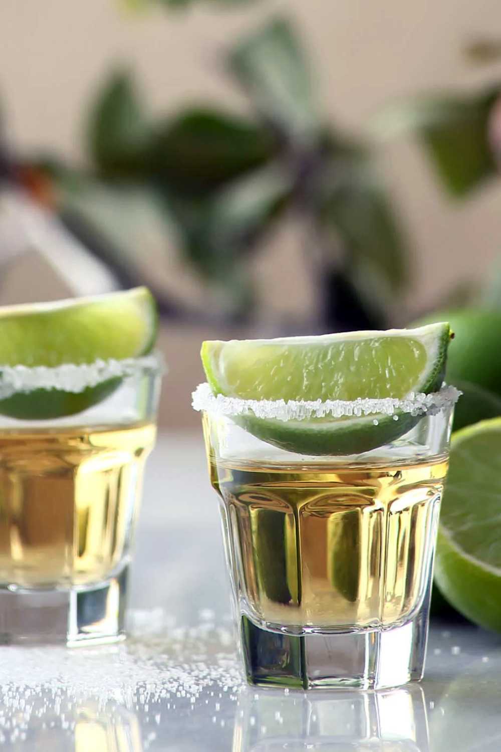 Reposado tequila in shot glass rimmed with salt with lime on top.
