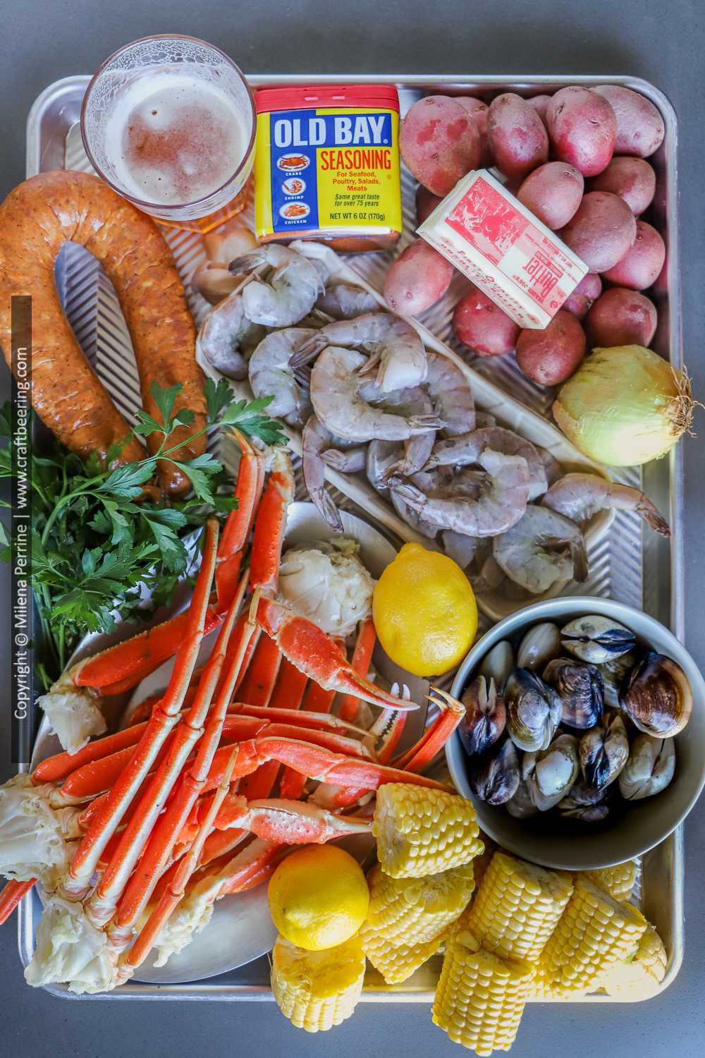 Ingredients for sea food boil bag - snow crab clusters, shrimp, clams, sausage, red potatoes, corn, onions, spices, Old Bay seasoning, parsley, lemons, butter, beer.