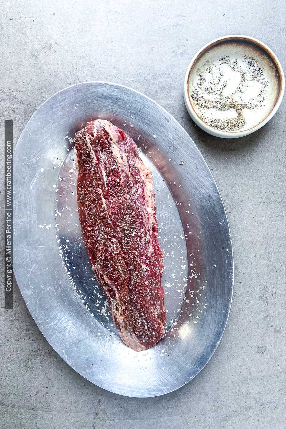 Raw teres major steak simply seasoned with salt and pepper.