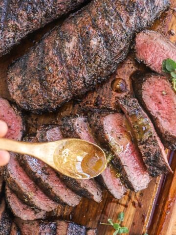 Whole grilled lamb loin is shown next to a sliced lamb loin that is being drizzled with sauce.