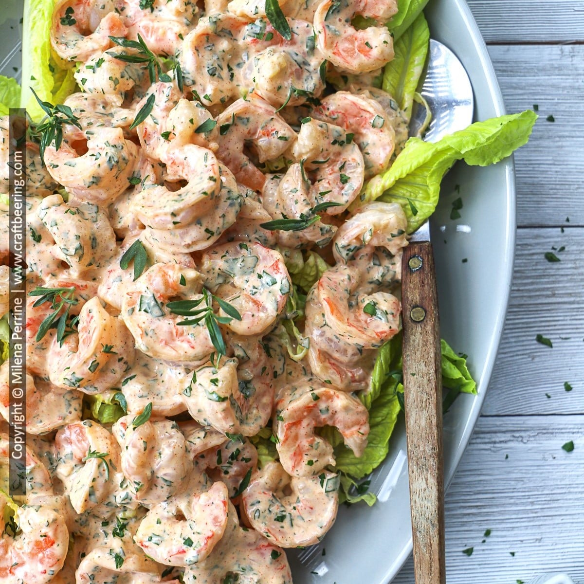 Classic shrimp remoulade is shown served on a platter with poached shrimp tossed in Cajum remoulade sauce in focus.
