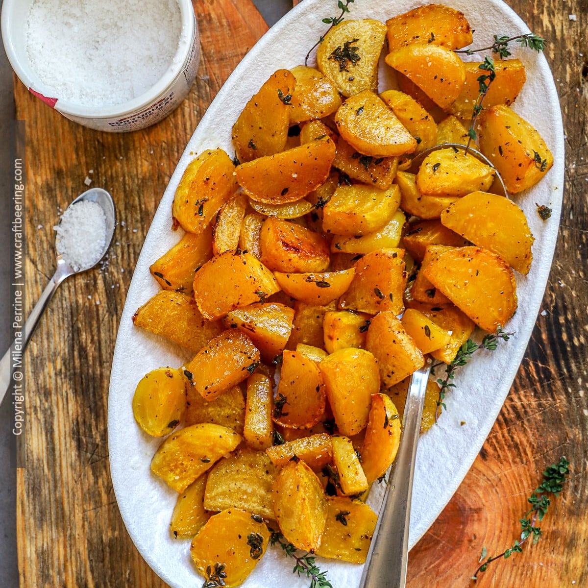 Roasted yellow beets are shown served in a white platter and garnished with thyme.