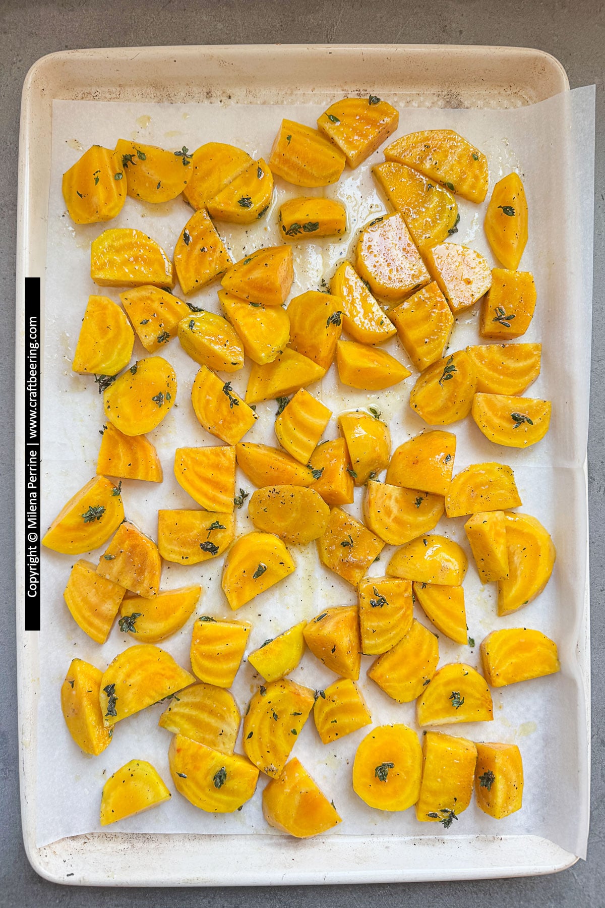 Yellow beets are shown cut into wedges, tossed in olive oil, seasonings and spreado over a baking sheet lined with parchment paper.