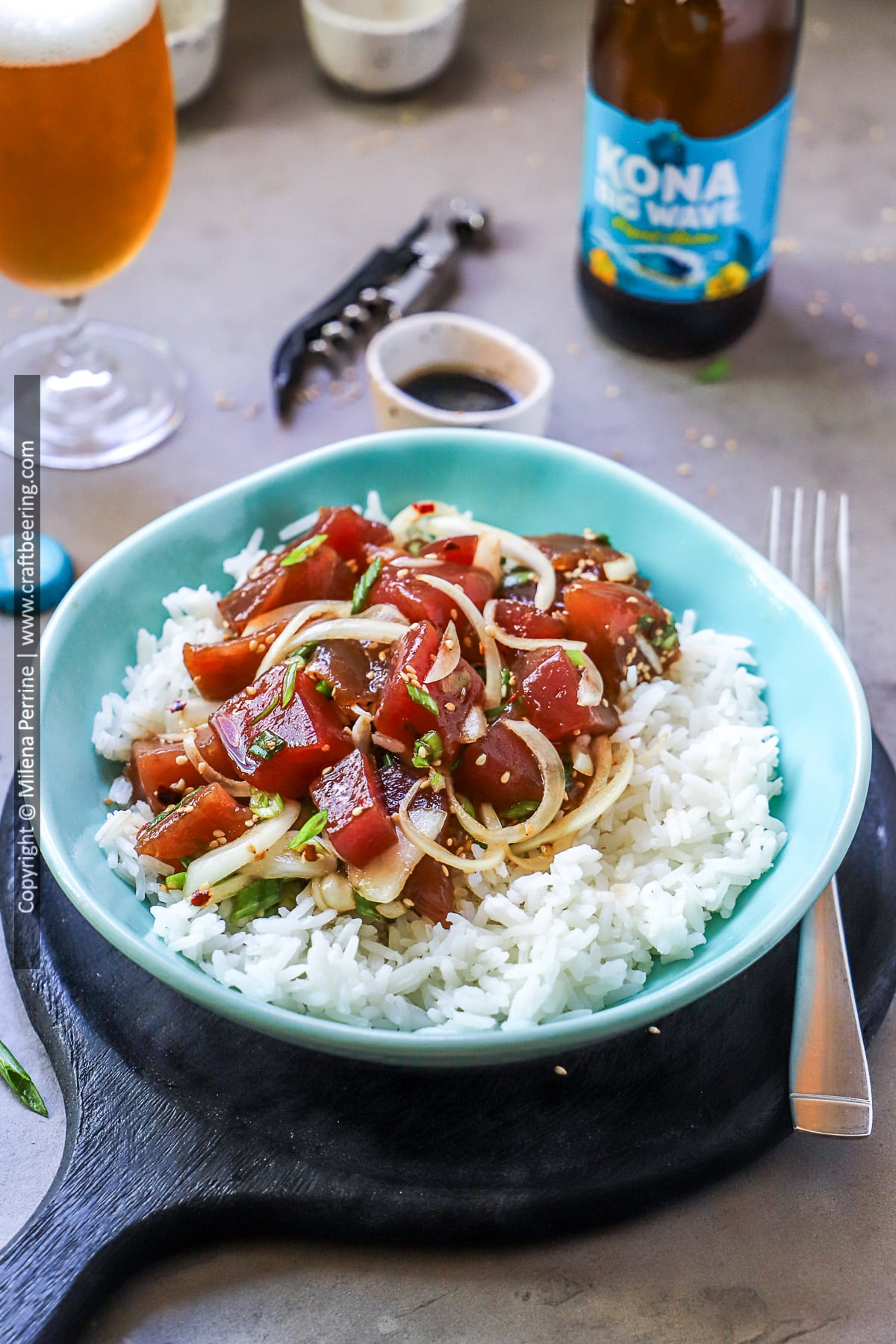Hawaiian poke bowl with ahi tuna and rice in a blue dish against a dark wood background.
