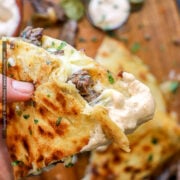 Quesadilla sauce is shown smeared over the tip of a steak quesadilla wedge held in focus.