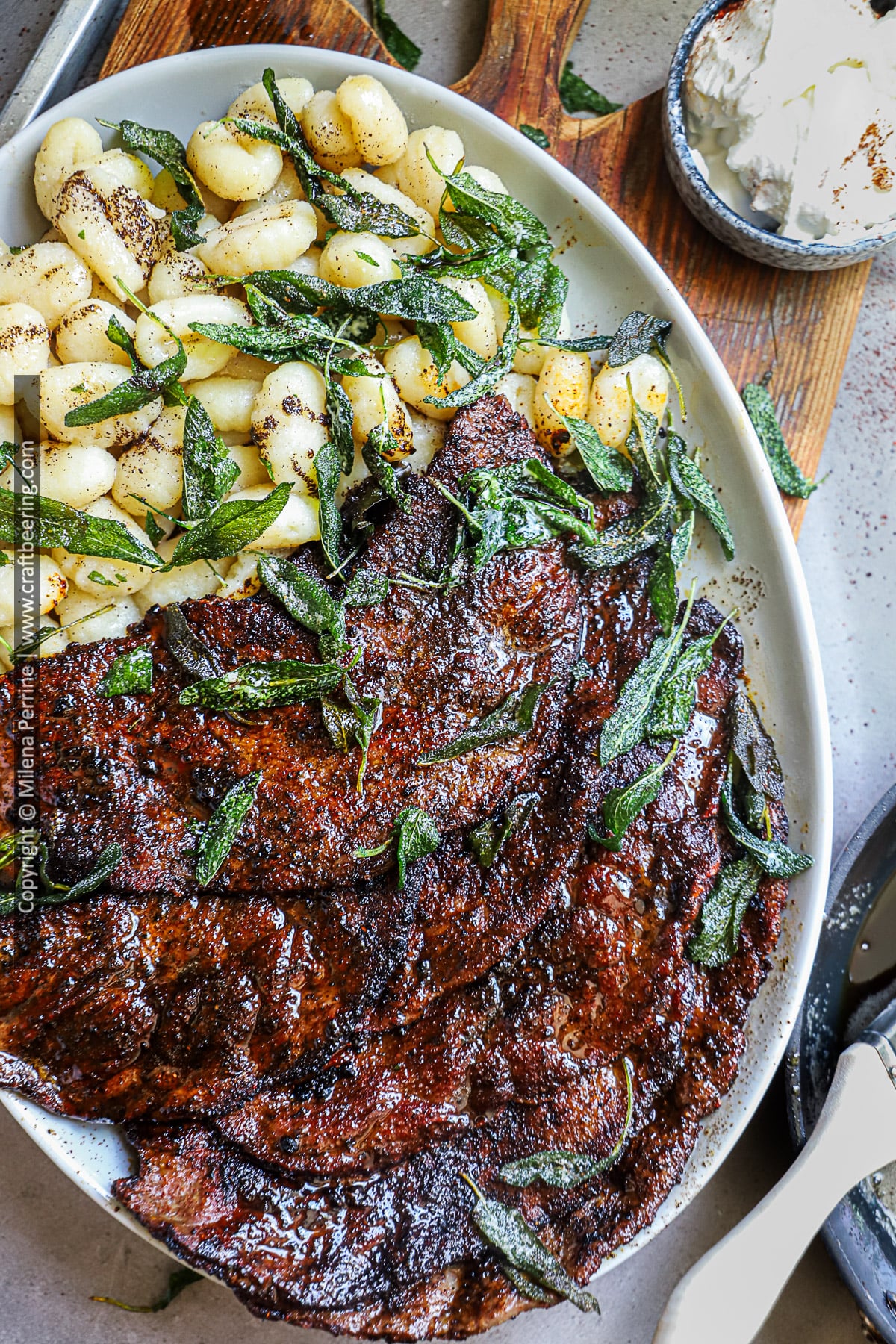 Minute steak from top round beef sliced thinly is shown seared an served on a platter with sage brown butter gnocci,