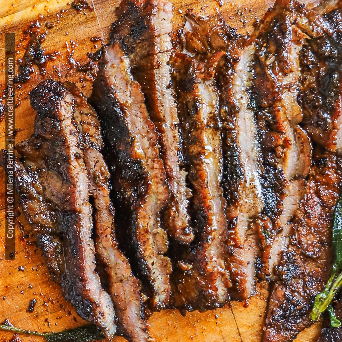 Top tender steak is shown sliced thinly over a wooden cutting board.
