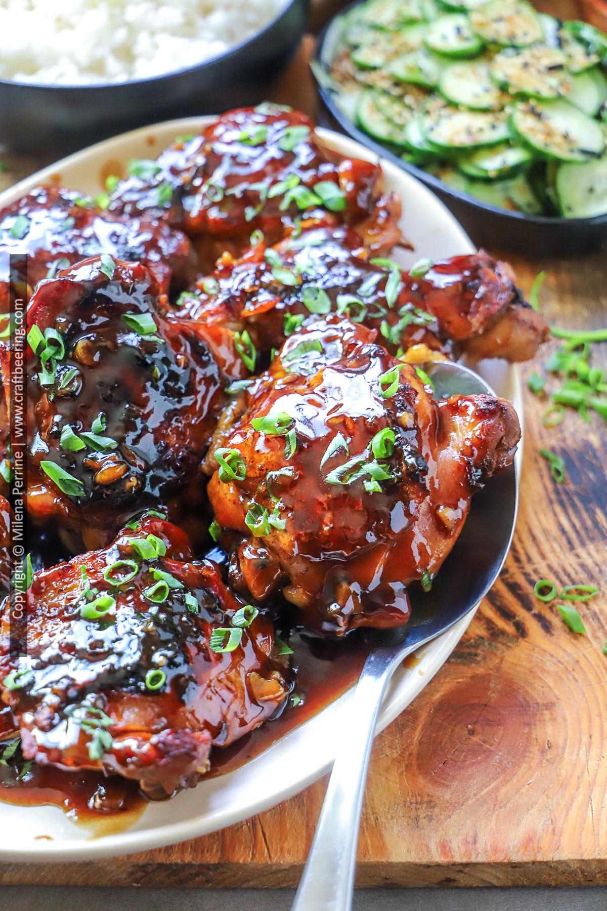 Hawaiian shoyu chicken is shown served on a white platter, garnished with green onions.