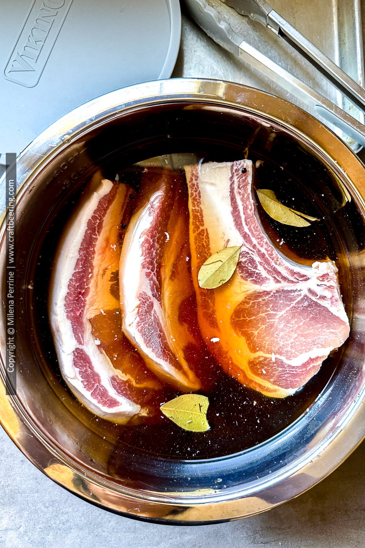 Thick cut bone in pork chops are shown in brine, viewed from above.