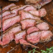Top sirloin steak is shown sliced revealing medium-rare juicy beef cut against the grain.