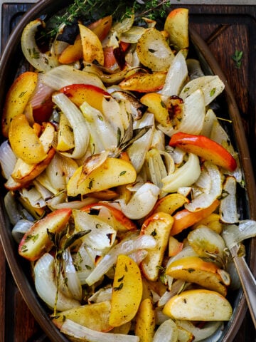 Baked apples and onions with sage and thyme are shown in an oval serving dish.